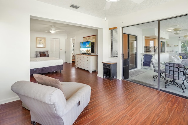 bedroom with a ceiling fan, wood finished floors, visible vents, and a textured ceiling