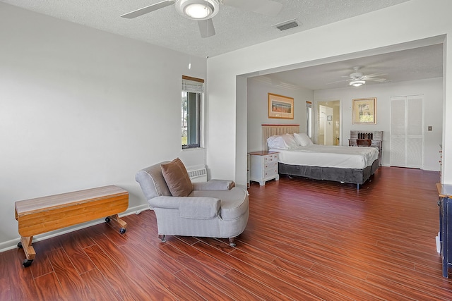 bedroom with visible vents, a textured ceiling, wood finished floors, baseboards, and ceiling fan