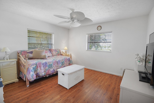 bedroom featuring multiple windows, a textured ceiling, and wood finished floors