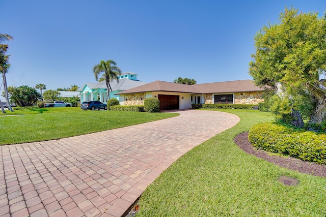 ranch-style home with a garage, decorative driveway, a front lawn, and stone siding