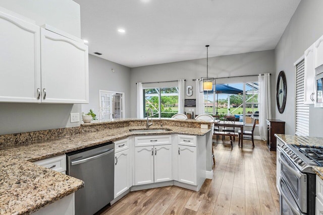 kitchen with light stone countertops, light wood-type flooring, white cabinets, stainless steel appliances, and a sink