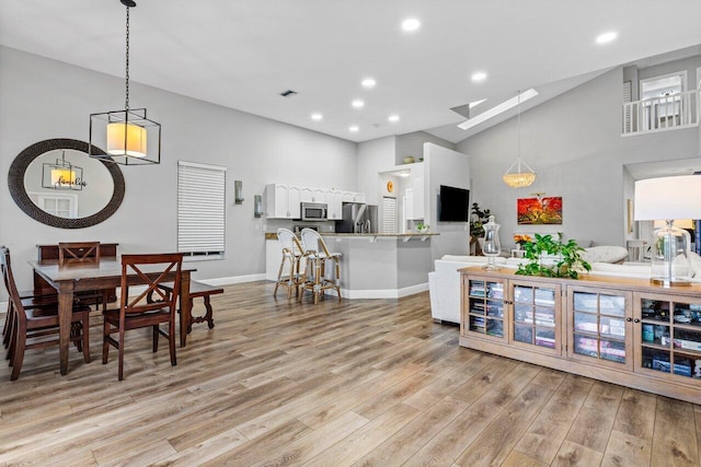 kitchen featuring light wood-style flooring, a skylight, white cabinets, appliances with stainless steel finishes, and decorative light fixtures