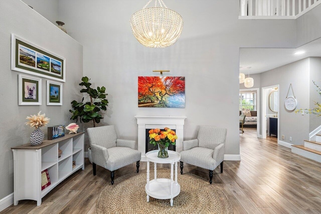 living area with wood finished floors, a high ceiling, and a chandelier