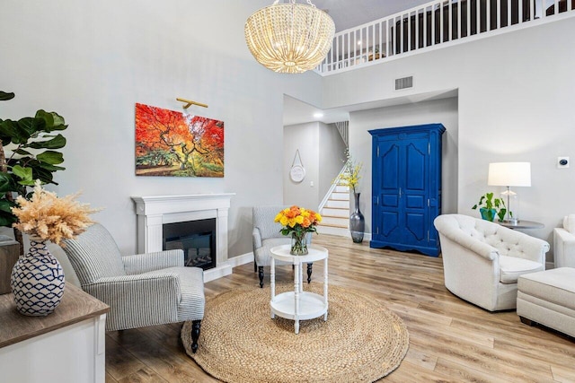 living area with a glass covered fireplace, visible vents, wood finished floors, and stairs