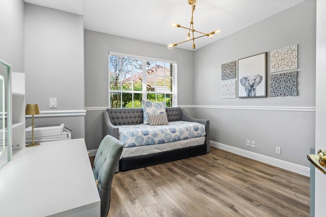 home office featuring a chandelier, baseboards, and wood finished floors