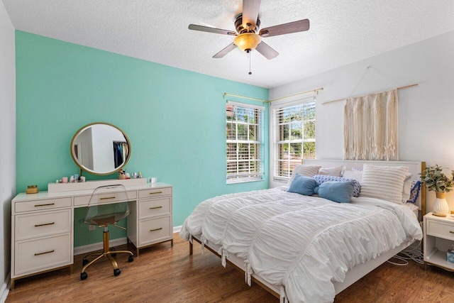 bedroom with baseboards, a textured ceiling, wood finished floors, and a ceiling fan