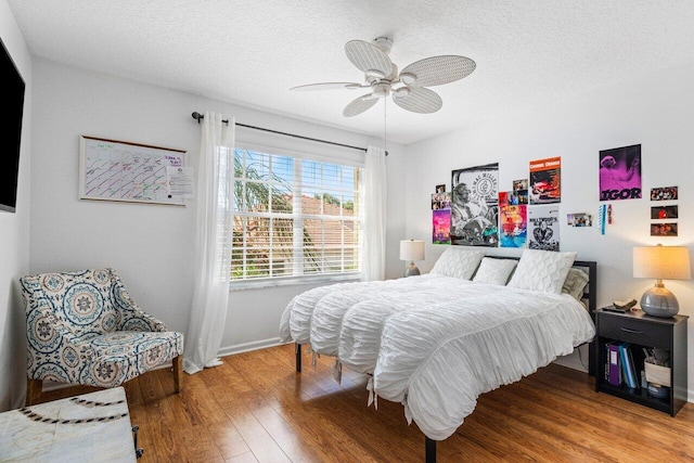 bedroom featuring ceiling fan, wood finished floors, and a textured ceiling