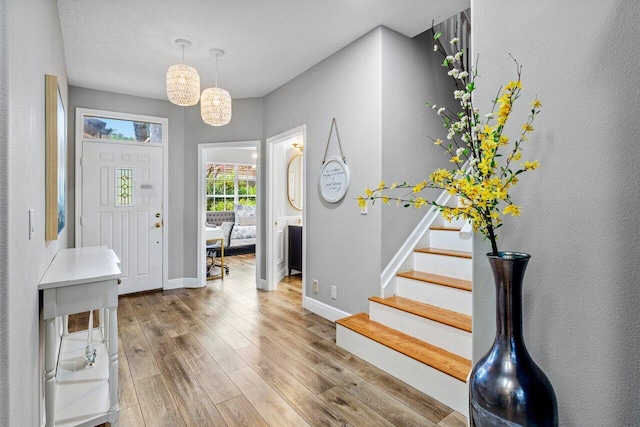 foyer featuring stairs, wood finished floors, and baseboards