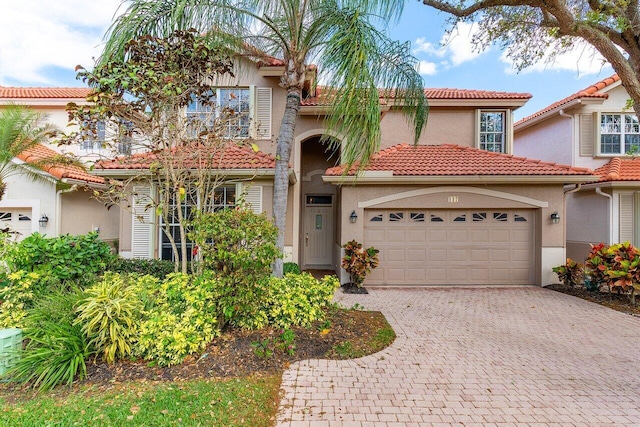 mediterranean / spanish house featuring stucco siding, decorative driveway, a garage, and a tile roof