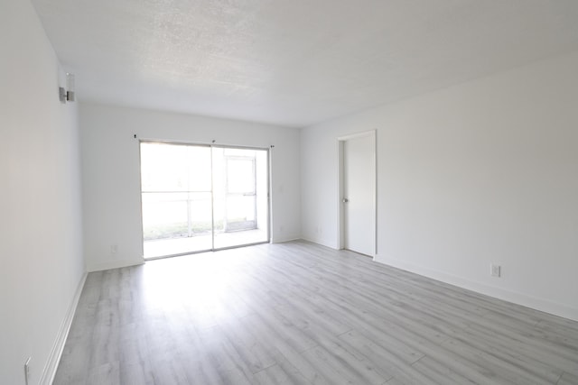 spare room with light wood-type flooring and baseboards