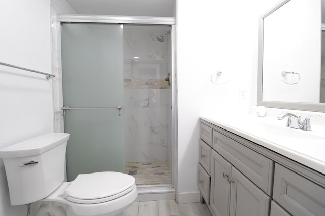 full bath with a marble finish shower, toilet, and vanity