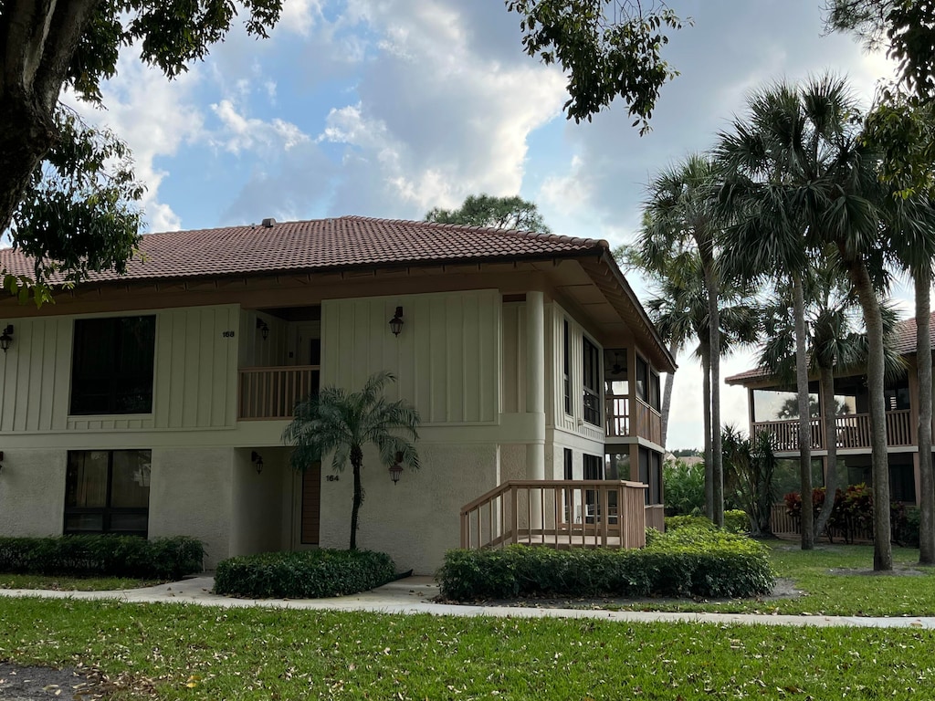 exterior space with a tile roof, a lawn, and stucco siding