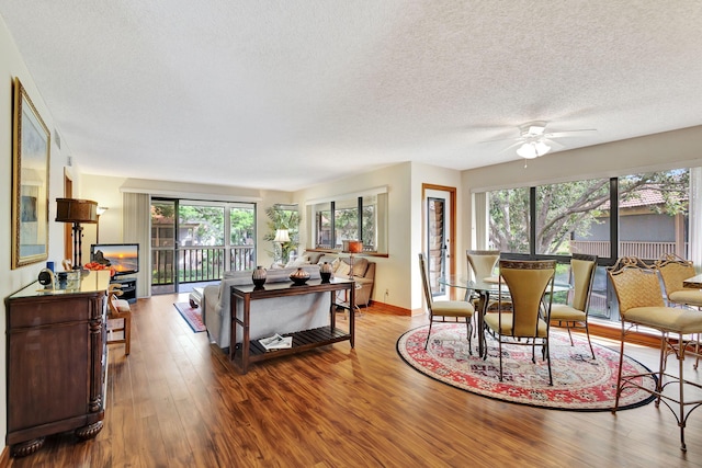 living area featuring baseboards, a textured ceiling, wood finished floors, and a ceiling fan