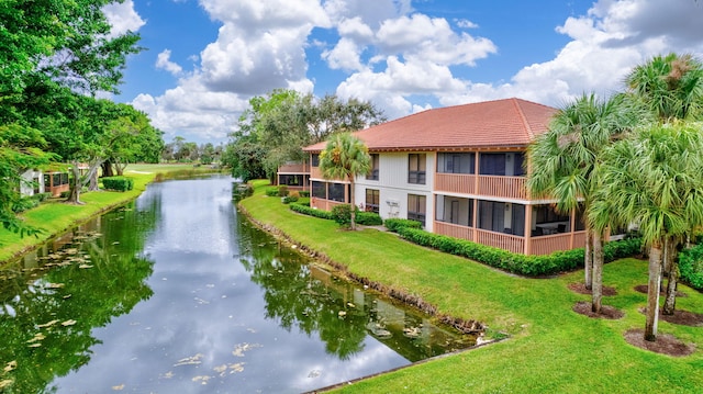 view of property's community featuring a lawn, driveway, and a water view