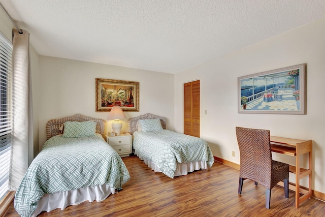 bedroom featuring wood finished floors, baseboards, a closet, and a textured ceiling