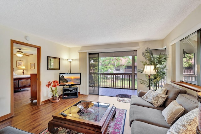 living room with baseboards, a textured ceiling, and wood finished floors