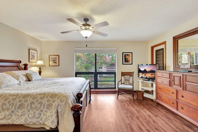 bedroom featuring a textured ceiling, light wood-style flooring, and a ceiling fan