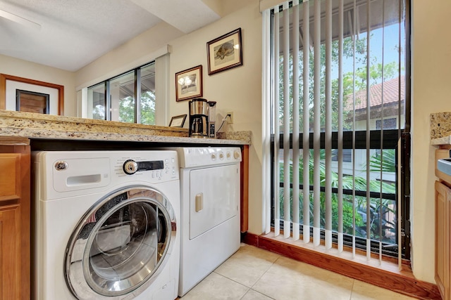 laundry room featuring washer and dryer, a wealth of natural light, laundry area, and light tile patterned floors