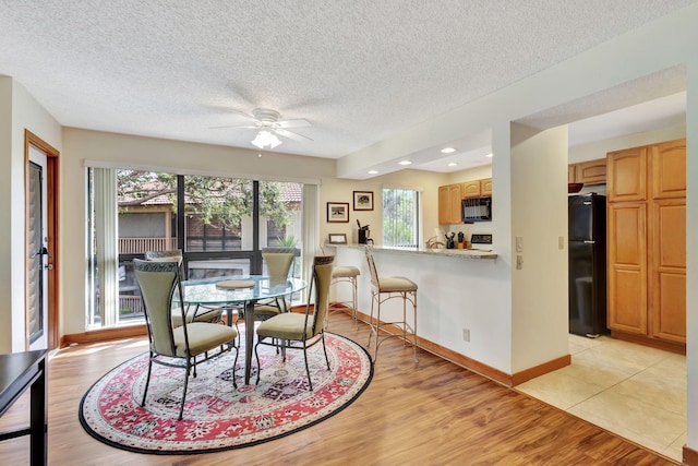 dining room featuring baseboards, light wood-type flooring, and a ceiling fan