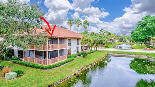 rear view of property with a yard, a water view, and a sunroom