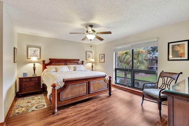 bedroom featuring baseboards, a textured ceiling, ceiling fan, and wood finished floors