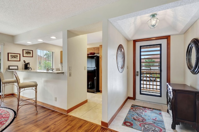 foyer featuring plenty of natural light, baseboards, light wood finished floors, and a textured ceiling