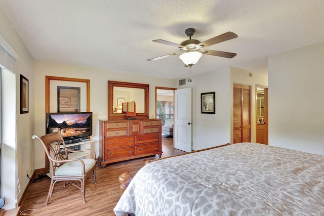 bedroom featuring visible vents, wood finished floors, a closet, a textured ceiling, and a ceiling fan