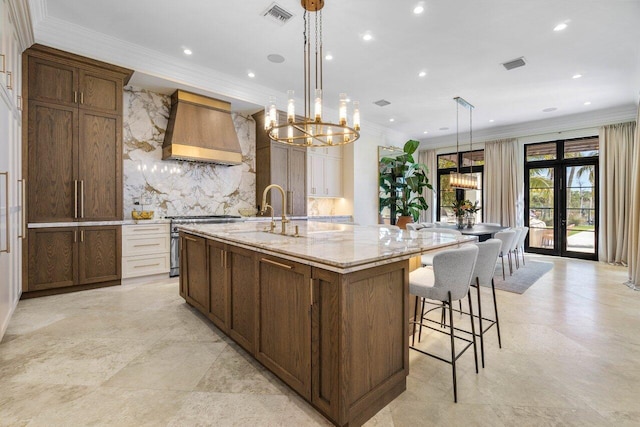 kitchen with high end range, visible vents, a sink, and premium range hood