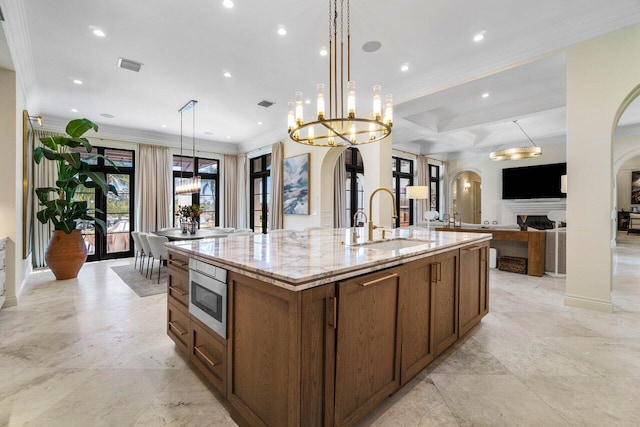 kitchen with visible vents, arched walkways, a sink, a large island, and stainless steel microwave