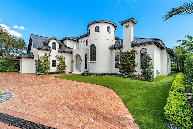 mediterranean / spanish-style house with stucco siding, metal roof, and a standing seam roof