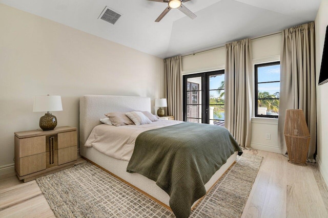 bedroom with visible vents, light wood-style flooring, a ceiling fan, baseboards, and lofted ceiling