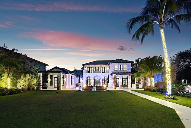 mediterranean / spanish home featuring french doors, metal roof, a yard, a patio area, and a standing seam roof