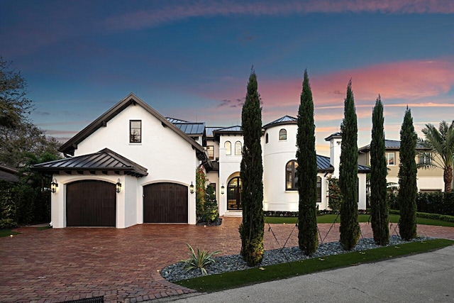 view of front facade featuring stucco siding, driveway, metal roof, and a standing seam roof