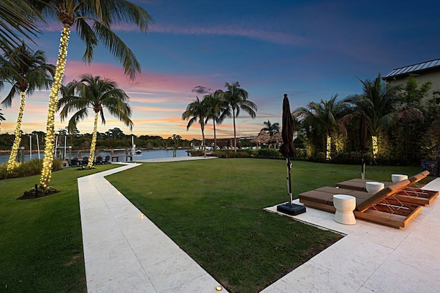 view of property's community featuring a boat dock, a yard, and a water view