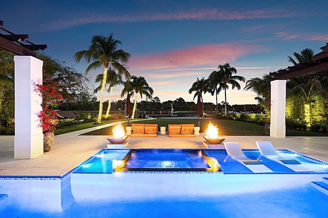 pool at dusk with a patio, a fire pit, and an outdoor pool