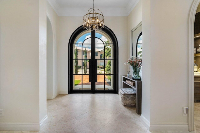 foyer featuring crown molding, baseboards, french doors, an inviting chandelier, and arched walkways