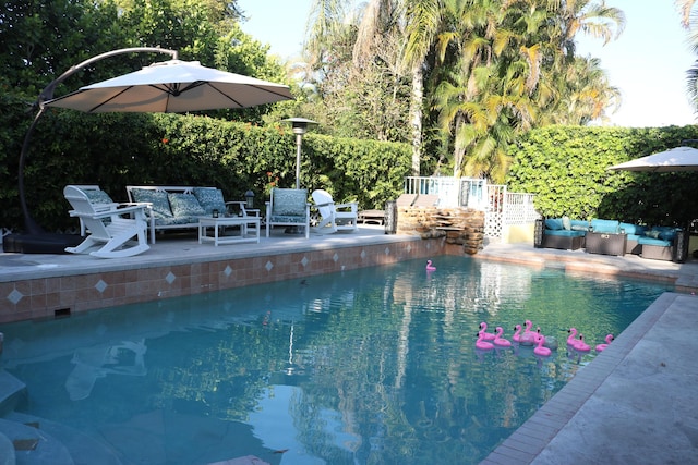 pool with an outdoor living space, a patio, and fence