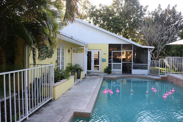 view of pool featuring a patio, a fenced in pool, fence, a sunroom, and french doors