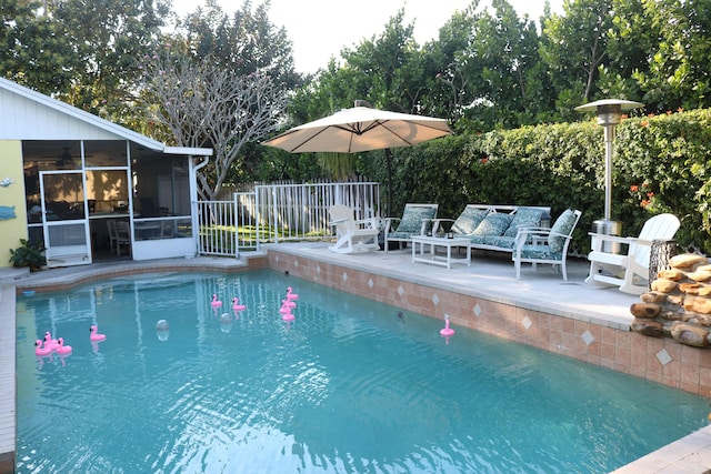 view of swimming pool featuring an outdoor living space, a patio, fence, a sunroom, and a fenced in pool