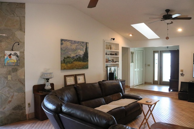 living room with a skylight, a ceiling fan, light wood-type flooring, and high vaulted ceiling