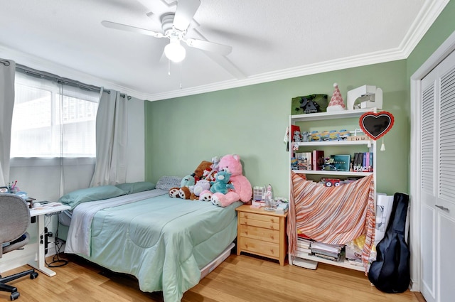 bedroom featuring ceiling fan, a closet, wood finished floors, and ornamental molding