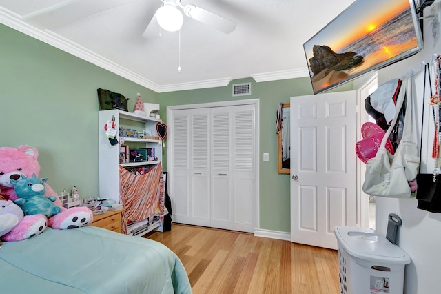 bedroom featuring light wood finished floors, visible vents, crown molding, a closet, and a ceiling fan