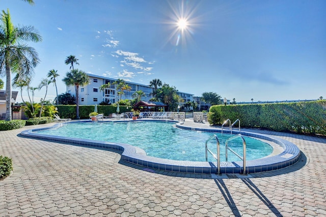 community pool with a patio area and fence