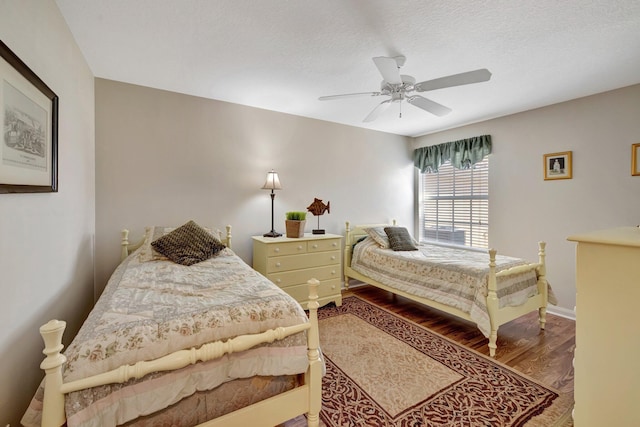 bedroom featuring a textured ceiling, wood finished floors, baseboards, and a ceiling fan