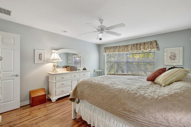bedroom with a ceiling fan, baseboards, light wood finished floors, and visible vents