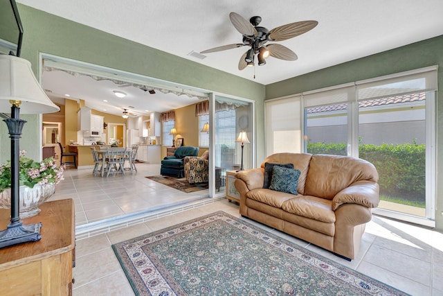 living room with tile patterned floors, visible vents, and ceiling fan