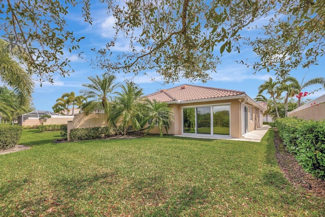 rear view of property with a lawn, a tiled roof, and stucco siding