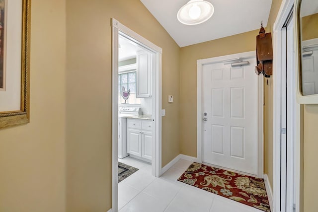 doorway to outside with light tile patterned floors, baseboards, and washer / clothes dryer