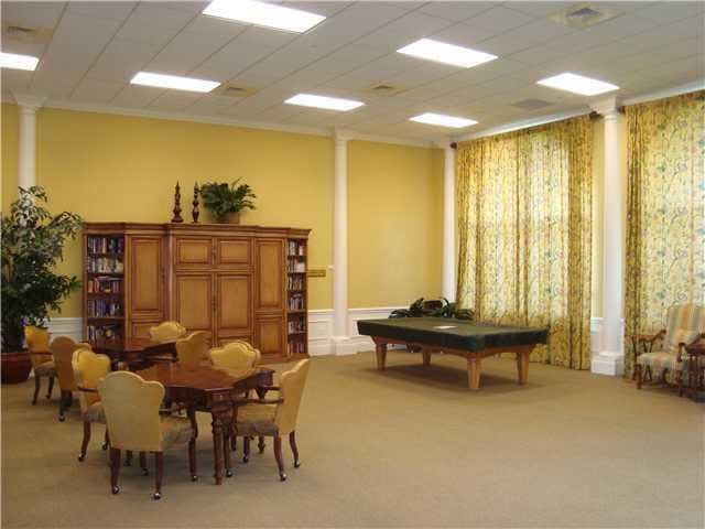 interior space featuring a wainscoted wall, a decorative wall, light colored carpet, ornamental molding, and ornate columns