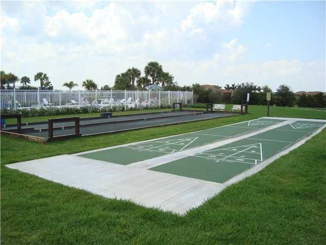 view of home's community with a lawn, fence, and shuffleboard